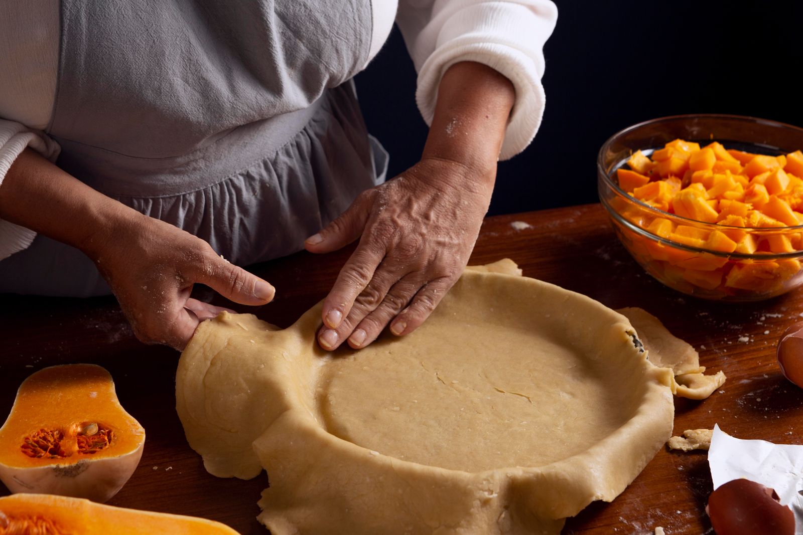 Pastry being pressed into a pie tin by hand